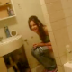 A friend sneaks into the bathroom to record Alyssa finishing up her pee visit.